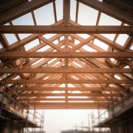 Dachstuhl aus Holzträgern in einer offenen Baukonstruktion mit Tageslicht