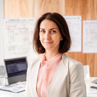 Claudia Scherrer in einem hellen Büro mit Holzmustern, Plänen und einem Laptop